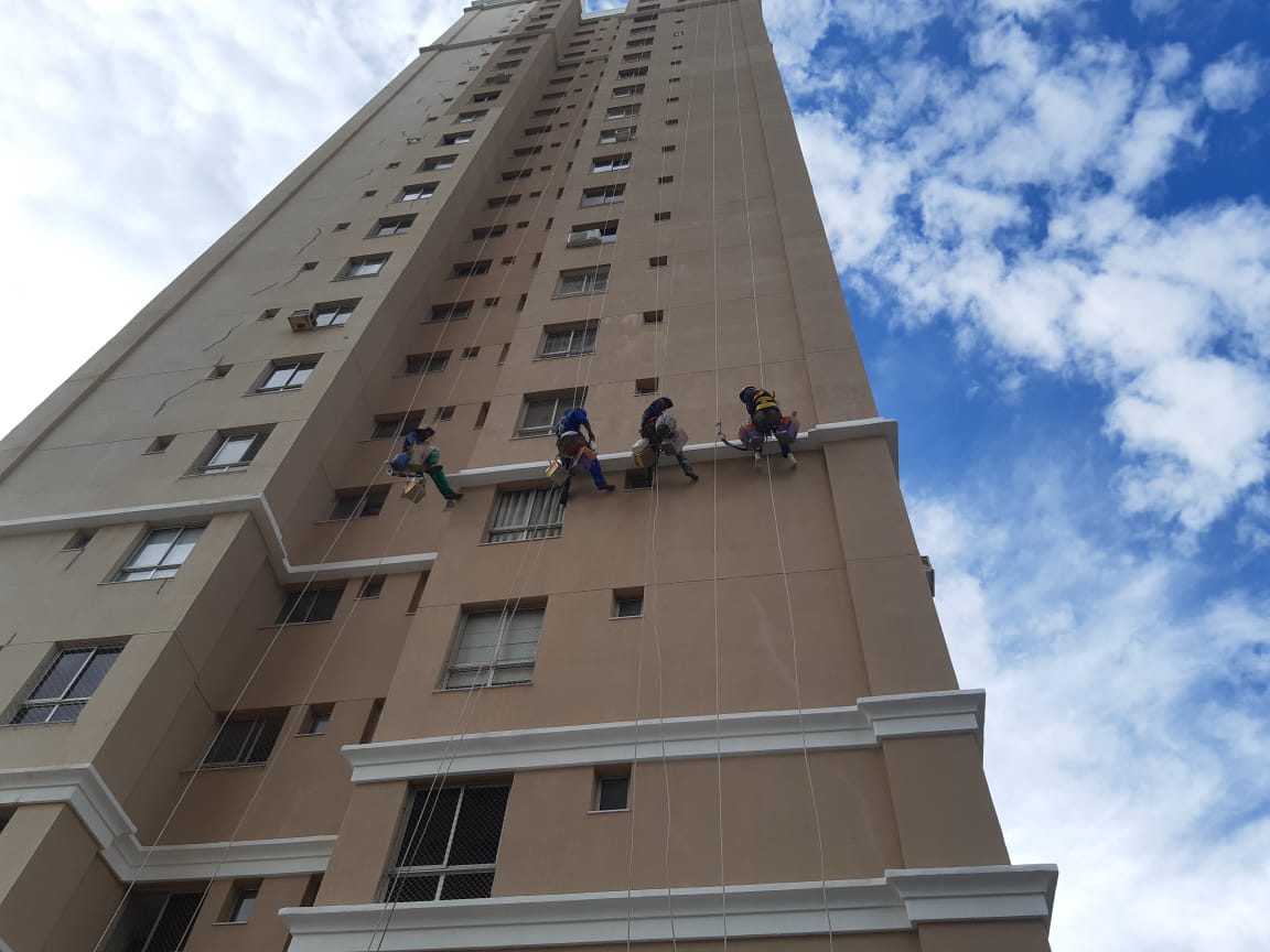 Alpinistas industriais executando recuperação de fachada predial